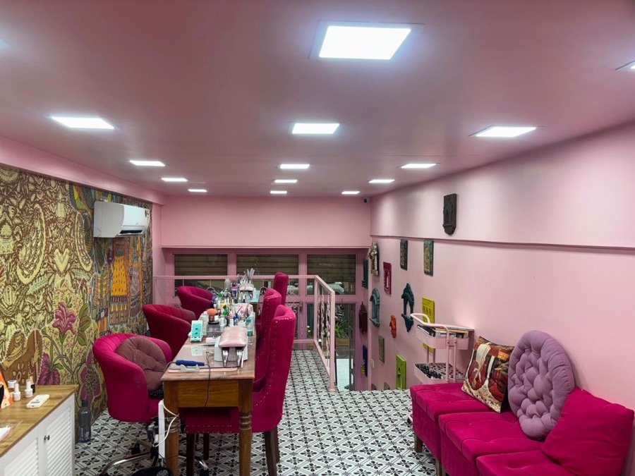 Manicure stations with floral wallpaper and pink chairs