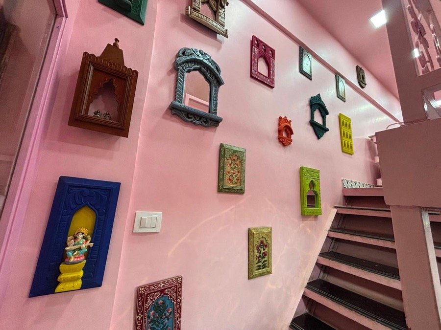 Pink feature wall with Rajasthani frames and Saraswati idol